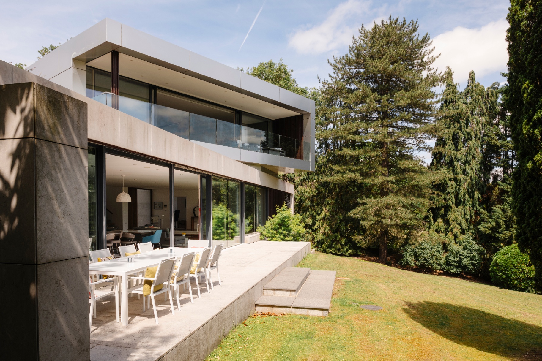 A contemporary country house with cantilevered upper storey, floor-to-ceiling glazing and a terrace overlooking mature gardens
